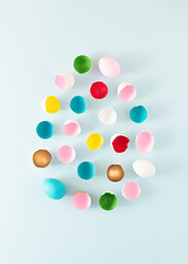 Creative egg shape composition made with Easter eggs and colorful eggshells on pastel blue background. Minimal holiday concept. Flat lay.