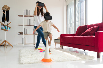 young asian kid and mom playing virtual reality game at home. family together concept