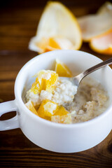 cooked boiled sweet oatmeal with oranges in a bowl