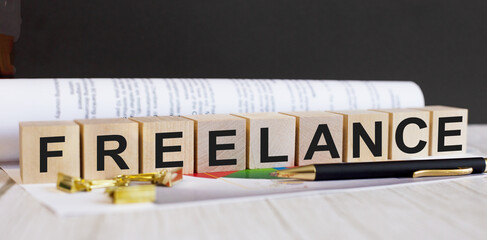 The word FREELANCE is written on wooden cubes near the pen and document.