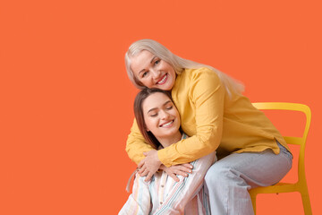 Portrait of young woman and her mother on color background