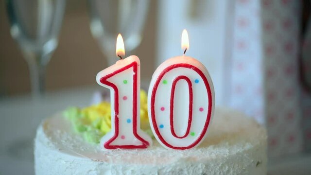Birthday candle as number ten 10 on top of sweet cake on the table, 10th birthday
