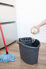 Close up of woman hand putting floor cleaners in the mop bucket.