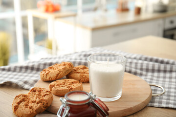 Aroma candle with cookies on table in kitchen
