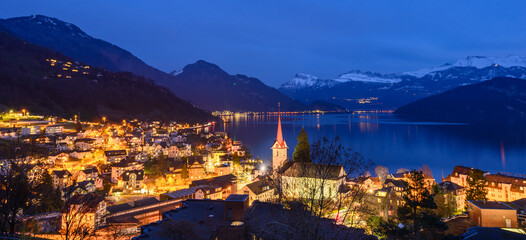 Night panorama. Lights of the city of Weggis. Switzerland. Lake Lucerne. The peaks of the Alps in the snow. - 419667766