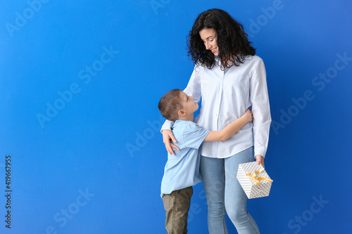 Little boy greeting his mom on Mother's Day against color background