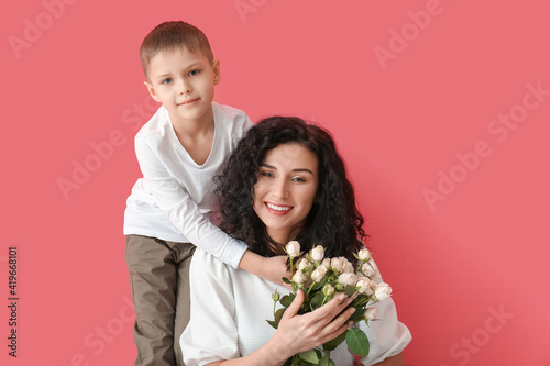 Little boy greeting his mom on Mother's Day against color background