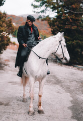 Stylish guy on a white horse