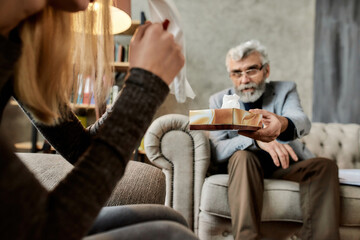 Mature psychotherapist giving napkin to crying woman