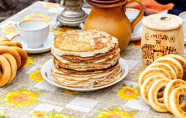 Stack of fried pancakes, bagels and ceramic tableware