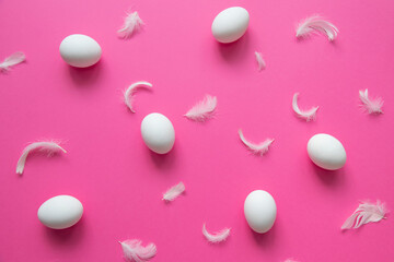 Trendy eggs pattern. Happy Easter. Flat-lay image of white eggs and feathers on a pink background. Minimalist style. 