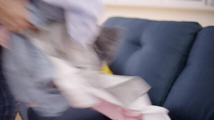 Man cleaning at home, picking up dirty clothes from the sofa, organizing tips