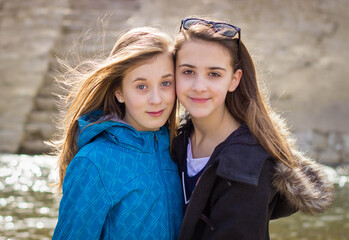 Two teen girls outdoors being affectionate with each other.