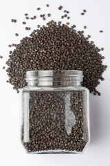 Close up of Organic Black Gram (Vigna mungo) or whole black urad spilled and in a glass jar. Top view 