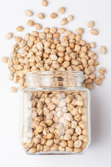 Close up of Organic small chhole chana or Kabuli chana (Cicer arietinum) or whole white Bengal gram dal spilled and in a glass jar. Top view 