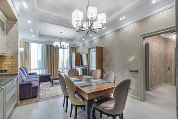 The light and spacious kitchen combined with the living room. New modern design of the chandelier. Large lounge area with a soft velvet sofa