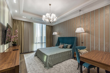 Classic interior of the bedroom..A TV above the wooden cabinet and a wooden wardrobe. Daylight going through  big French windows