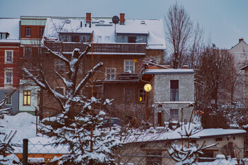 Häuser mit beleuchteter Uhr im Winter bei Schnee