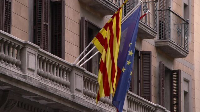 Lockdown: Flags Of Catalonia Spain And Eu Sway Gently In Breeze From Decorative Balcony Of Striking Elegant Building