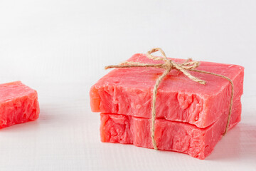 Stack of handmade soap bars on white table. Pink homemade soap tied with natural rope.