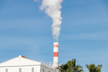 Exhaust chimney of the chemical industry with the smoke in Palos de la Frontera in Huelva, Andalusia, Spain.