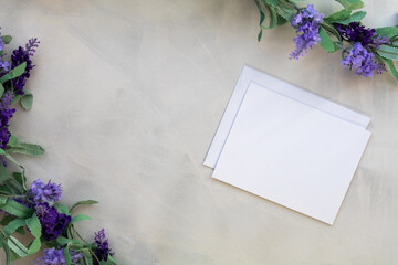 White notecard mockup and lilac on gray wash background flat lay copy space