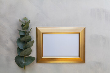 Gold frame mockup and eucalyptus on gray wash background flat lay copy space