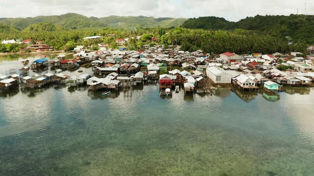 Old wooden house standing on the sea in the fishing village, aerial view. Dapa, Siargao, Philippines.