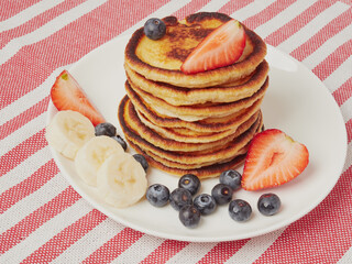 Close-up of delicious pancakes, with fresh blueberries, strawberries and maple syrup on a light...