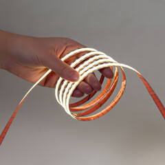 Hands holding flexible glowing LED strip over white background