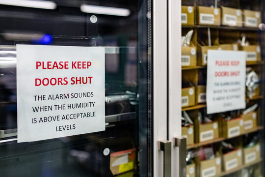 Close up of a sign on a moisture sensitive cabinet in a electronics manufacturer warning people to keep doors closed to protect the raw components inside