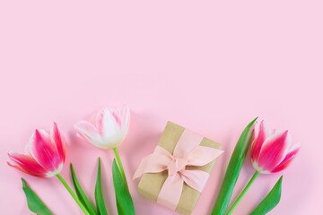 Colorful tulips and gift box on pink background.