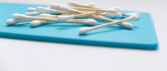 Pile of biodegradable bamboo cotton buds on blue board with copyspace
