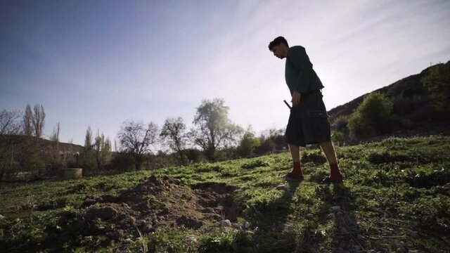 Joven agricultor cava agujero en el huerto con una azada con calidad cinematogr&aacute;fica a c&aacute;mara lenta 