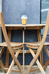 Fototapeta na wymiar Iced coffee or frappuccino with cream in takeaway disposable cup on wooden table and two chairs