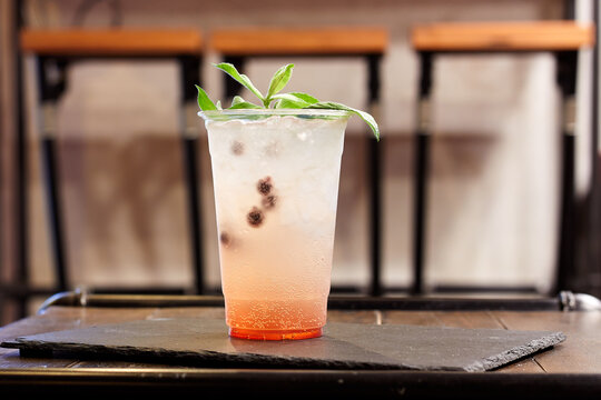 Lemonade with mint and currants in a plastic disposable cup on table