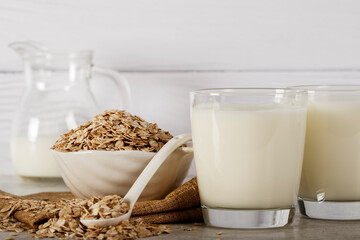 Oatmeal in a white bowl with a glass of milk on a white blue background. A healthy, nutritious morning breakfast. Oat milk. Healthy vegan non-dairy organic drink with flakes. 