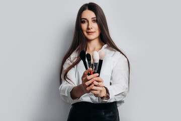 Makeup artist with brushes in hand on a white background