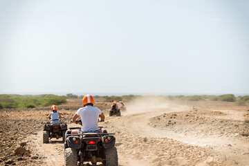 People quad biking across desert terrain