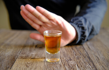 A man is using his hand to signal that he will refuse a glass of wine