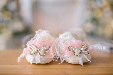 little baby booties with pink bows and decorative butterflies on the background of garland lights