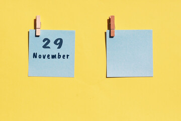 29 november. 29th day of the month, calendar date. Two blue sheets for writing on a yellow background. Top view, copy space. Autumn month, day of the year concept