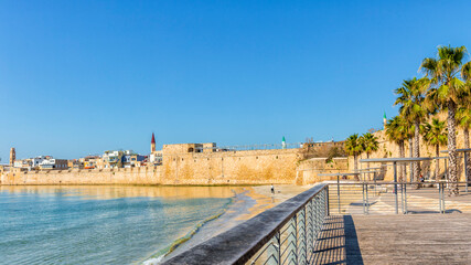 An old fortress wall with towers and defensive structures surrounding the ancient city of Akko in the Mediterranean Sea, Israel.