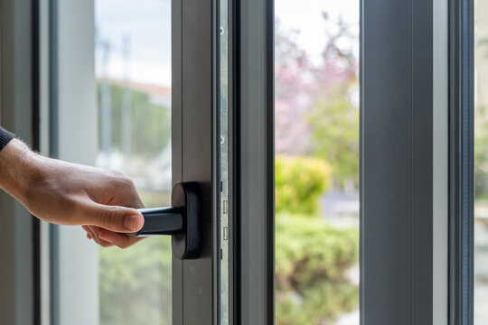 Aluminum window frame detail. Male hand opens the metal door closeup view.