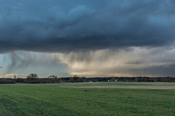 Fototapeta na wymiar Rainfall with dark clouds over green meadow