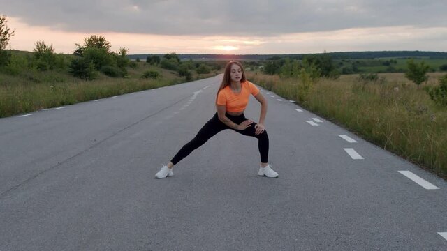 Sporty girl having workout on road at beautiful nature on sunset