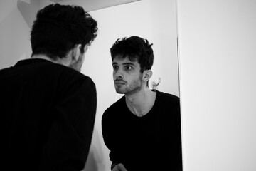Teenager observes himself facing à mirror on a bathroom