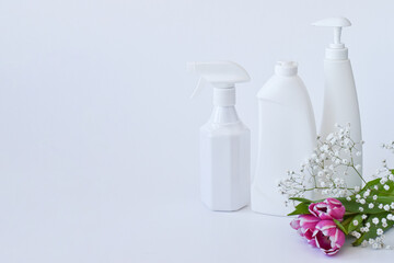 Cleaning products on white. Bottles of detergent and tulips. The concept of cleaning in the house, apartment, office. Household chemicals. Spring.