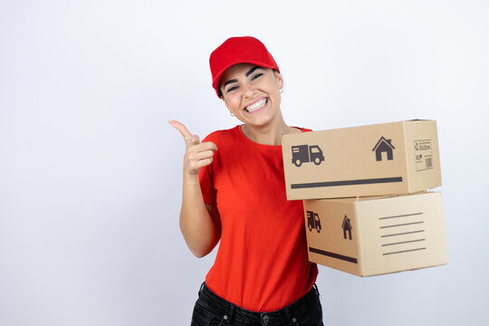 Young beautiful woman wearing courier uniform holding delivery packages pointing to you and the camera with fingers, smiling positive and cheerful