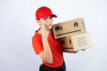 Young beautiful woman wearing courier uniform holding delivery packages Pointing to the eye watching you gesture, suspicious expression